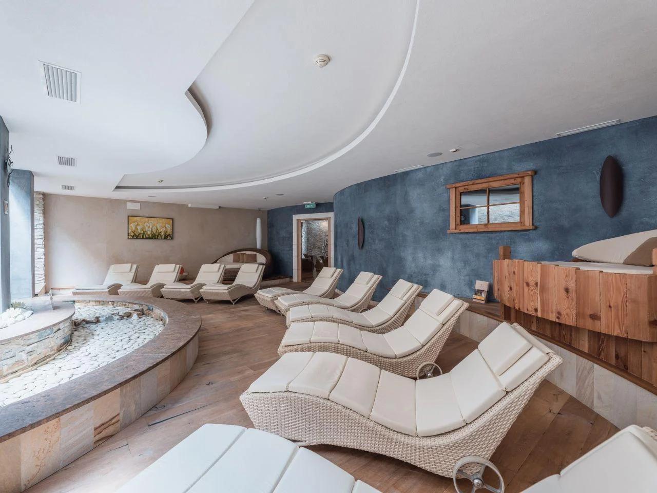 Strefa relaksu i spa w Tevini, Val di Sole, Włochy. Nowoczesne leżaki, basen z kamieniami, eleganckie oświetlenie, drewniane detale.