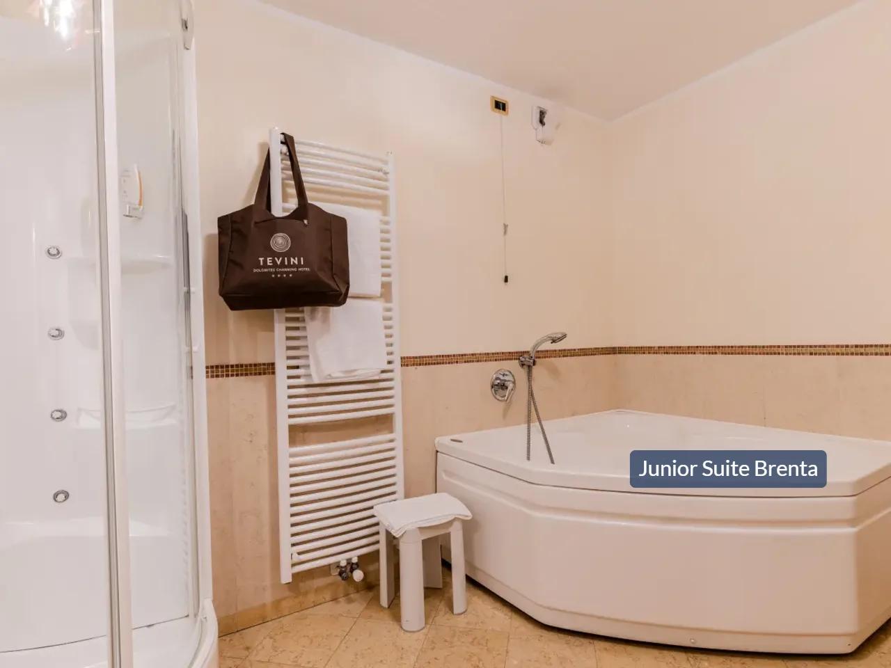 Łazienka Junior Suite Brenta w hotelu TEVINI, Val di Sole, Włochy. Prysznic, wanna narożna i grzejnik na ręczniki.