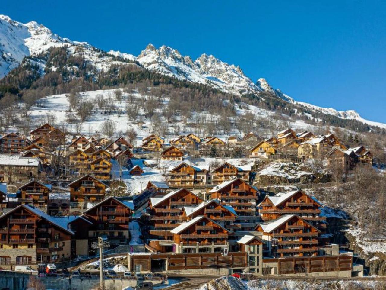 La Cascade, Alpe d'Huez: Ośnieżony kurort narciarski w Alpach Francuskich. Drewniane chalety na tle gór i błękitnego nieba.