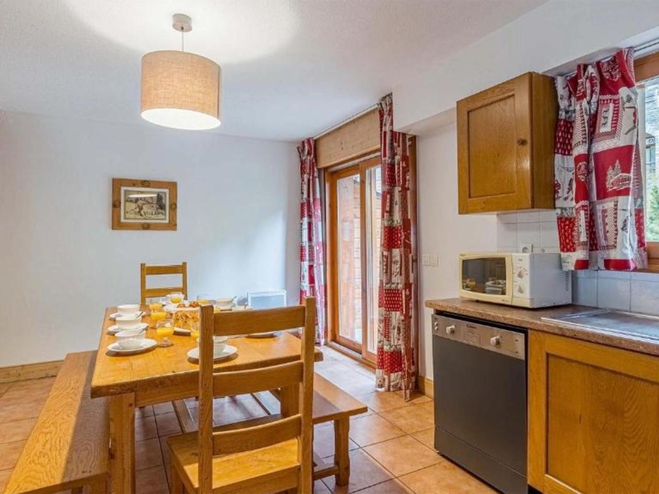 Jasna jadalnia i kuchnia w apartamencie La Cascade w Alpe D Huez, Francja. Drewniany stół z zastawą śniadaniową.
