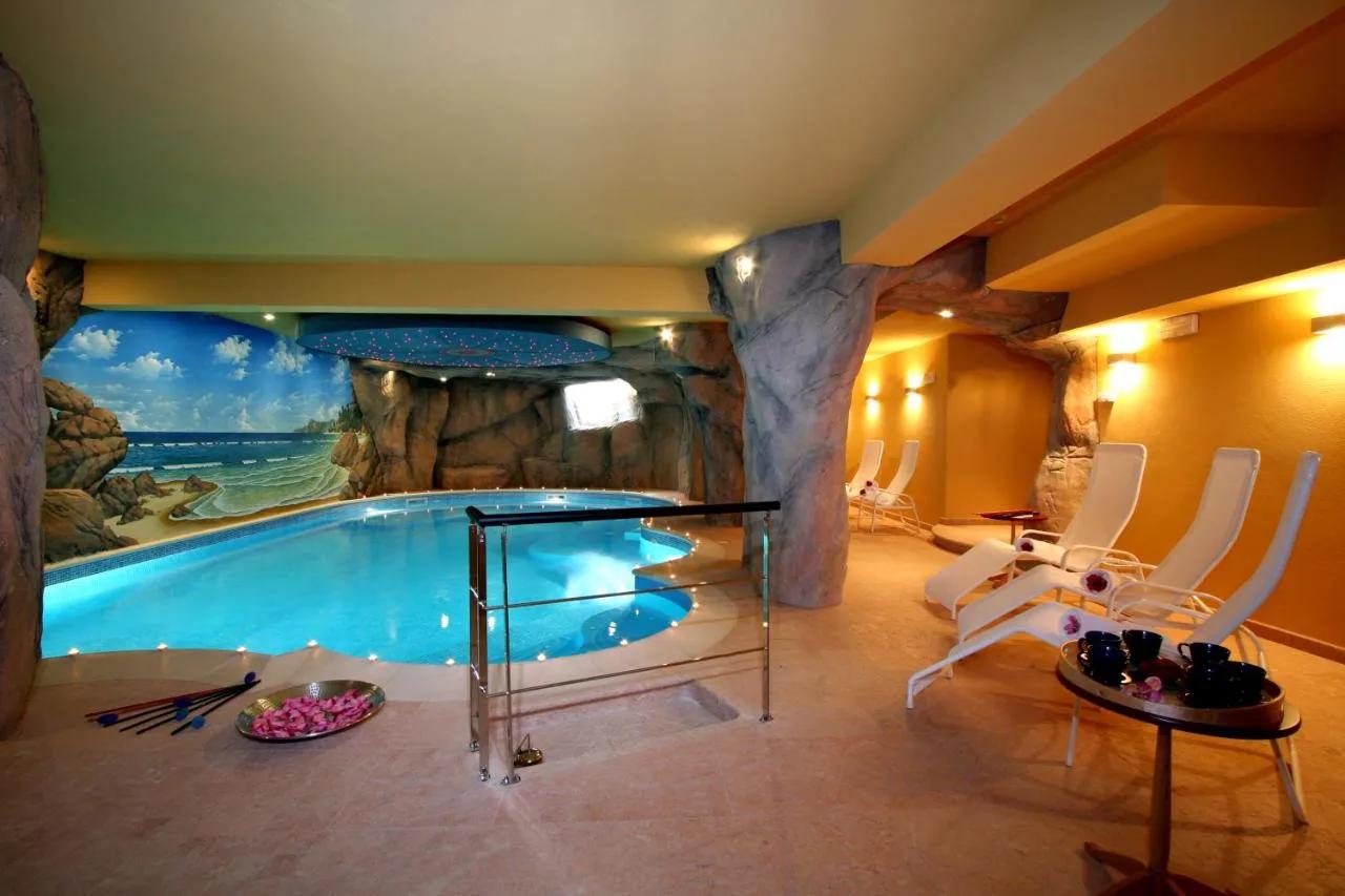 Luksusowy kryty basen w hotelu Paradise, Saint Vincent Aosta, Włochy. Jaskinia z muralem plaży i wygodnymi leżakami do relaksu.