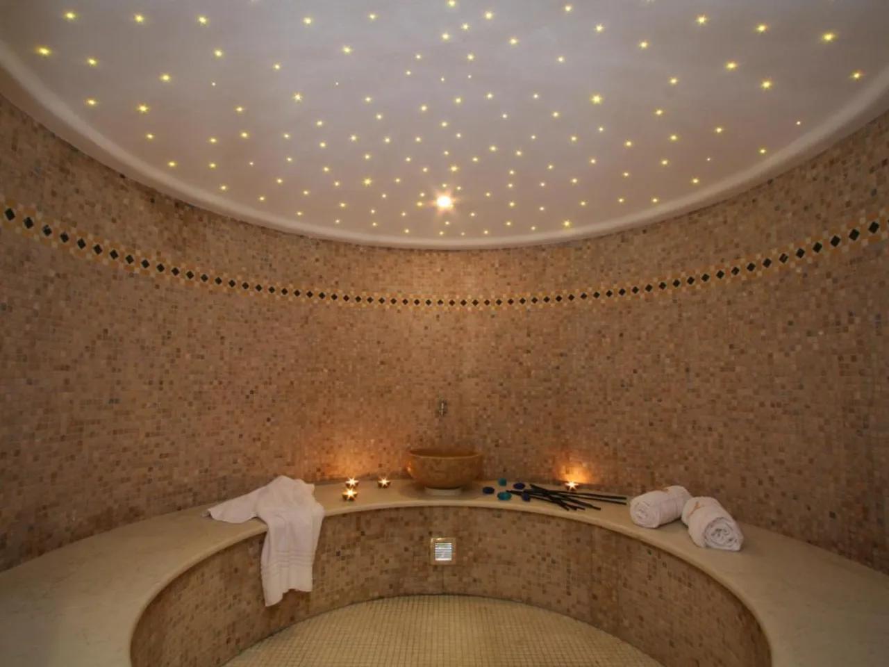 Luksusowe spa z mozaikowymi ścianami i gwieździstym sklepieniem. Jasne punkty świetlne tworzą relaksującą atmosferę.