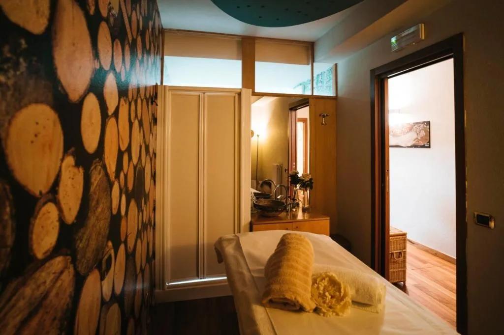 Przytulny pokój spa z drewnianą ścianą i stołem do masażu, z ręcznikami i umywalką w hotelu Paradise we Włoszech.