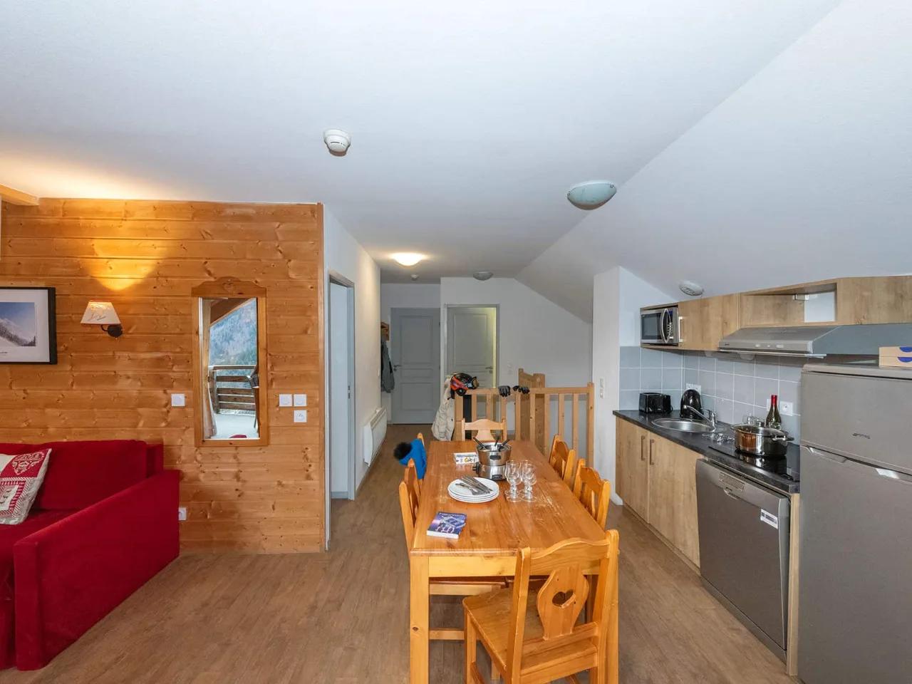 Przytulny apartament z otwartą kuchnią, salonem z sofą i drewnianą jadalnią, idealny na wakacje w górach.
